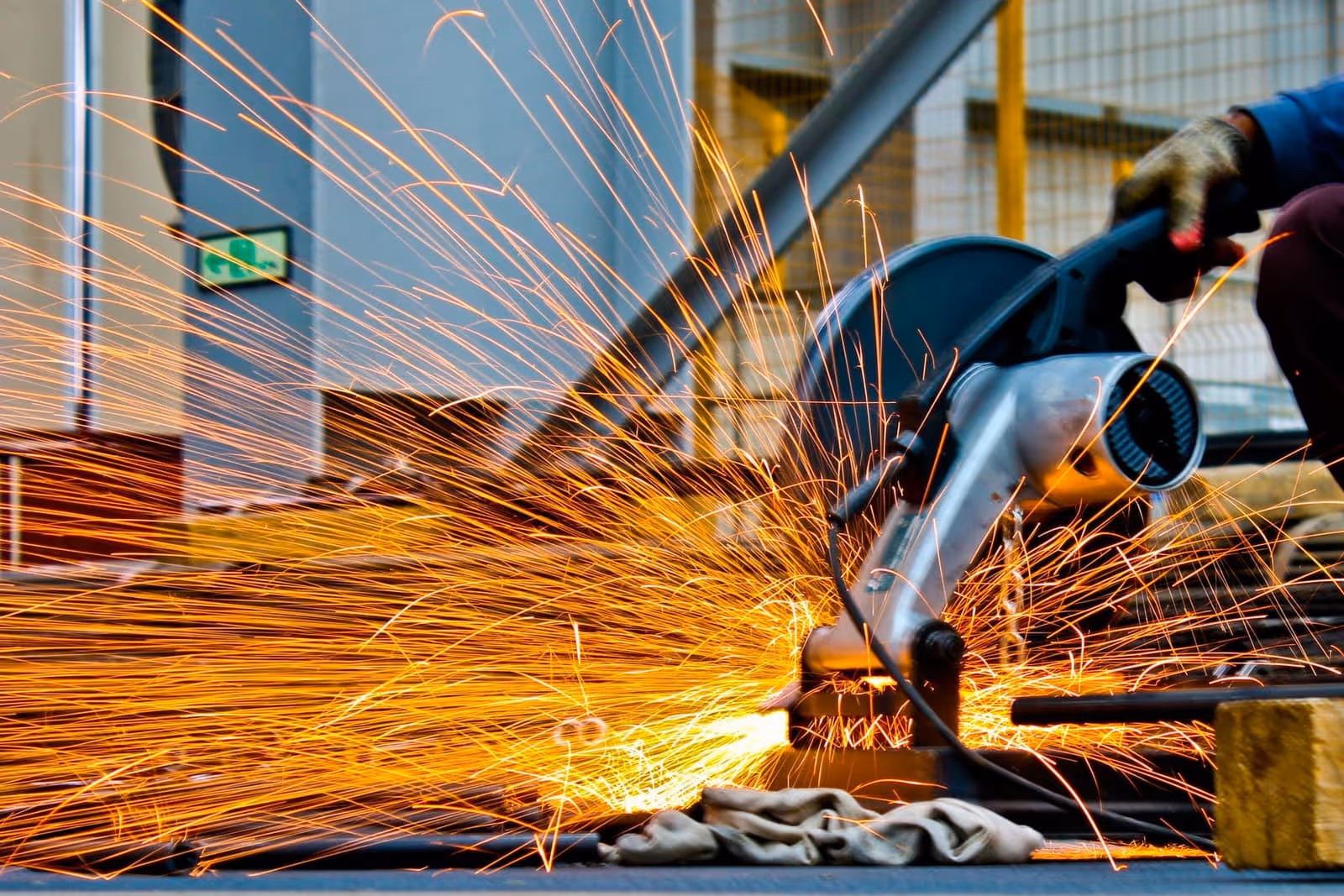 Troncatrice al lavoro su barra d'acciaio — scia di scintille durante il taglio in officina